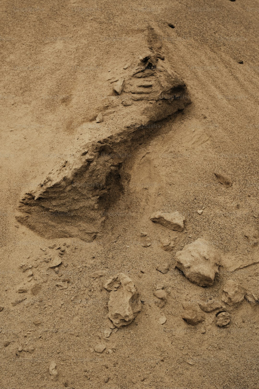A large rock in the middle of a dirt field