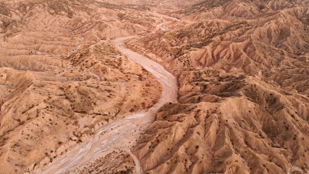 Aerial view of a dry, winding riverbed through desert hills.